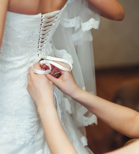 The bride's friend helps the bride to fasten the corset to an elegant wedding dress.