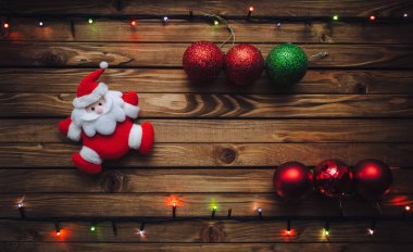Noel arka plan ile Santa Claus, Noel topları ve çelenk ile ahşap tahta üzerinde renkli ışıklar. Kartpostal kavramı.