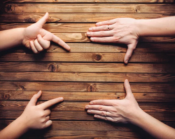 Girl's fingers points to empty spot intended for advertising. Wooden background.