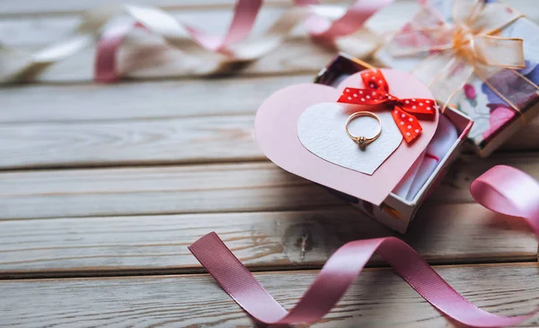 Marriage proposal concept. Wedding ring in gift box on wooden background. Valentine's Day. Festive decor.