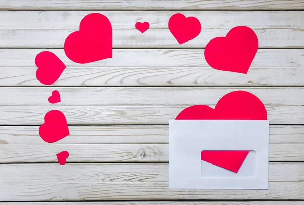 Red hearts in a white envelope. The concept of St. Valentine\'s Day. A letter for a loved one. A declaration of love.