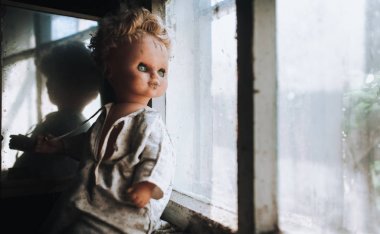 Kirli pencere kenarındaki eski bebek camın arkasından görünüyor. Korku, korku, Cadılar Bayramı