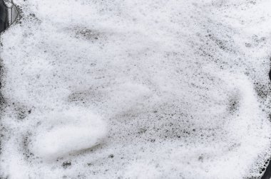 Siyah arka planda beyaz köpük ve sabun. Soyut model. Araba yıkama. Boşluğu kopyala.