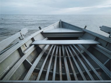 Düz tabanlı gri bir tekne deniz kıyısında duruyor. Sakin, demirli ve güzel hava kavramı. İç görünüm.