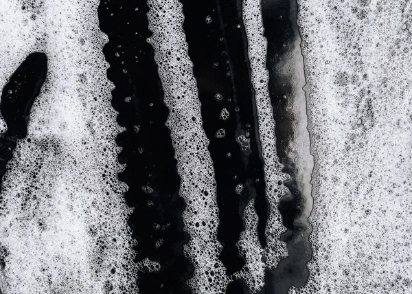 White foam and soap on black background. Guest worker concept. Abstract pattern. Car wash.