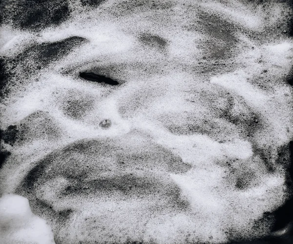 White foam and soap on black background. Abstract pattern. Car wash. Guest worker concept.