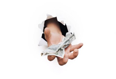 A male hand appears in the hole in torn white paper and offers two hundred-dollar bills. The concept of donation, poverty, benefits, scholarships, and generosity. clipart