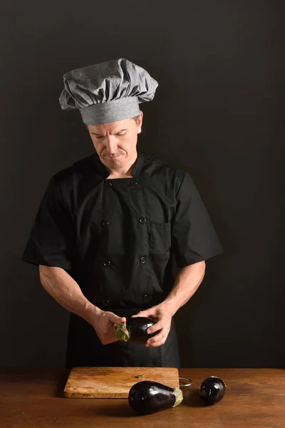 Szef kuchni cięcia bakłażan na czarnym tle — Zdjęcie stockowe