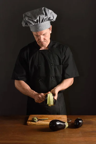 Szef kuchni cięcia bakłażan na czarnym tle — Zdjęcie stockowe