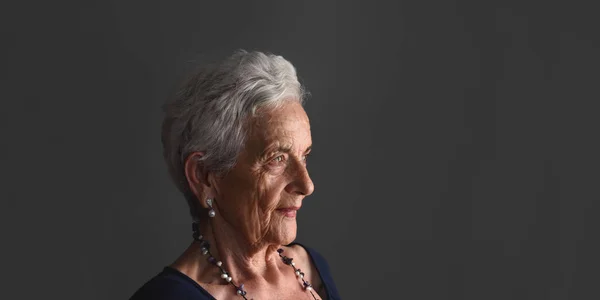 Retrato de una mujer mayor sobre fondo gris — Foto de Stock