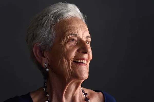 Porträtt av en äldre kvinna på grå bakgrund — Stockfoto