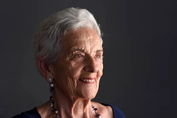 Retrato de uma mulher idosa em fundo cinza — Fotografia de Stock