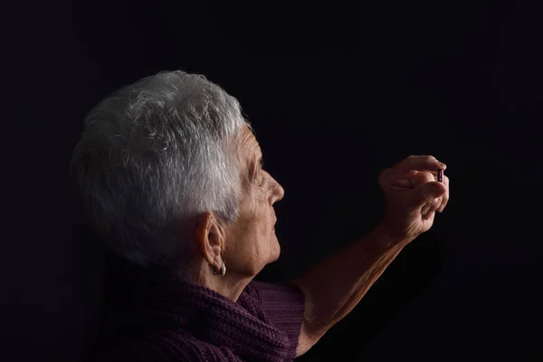 Femme âgée à la recherche d'une pilule avec fond gris — Photo
