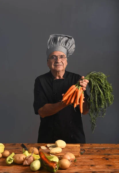 Portret szefa kuchni z marchewką na szary — Zdjęcie stockowe
