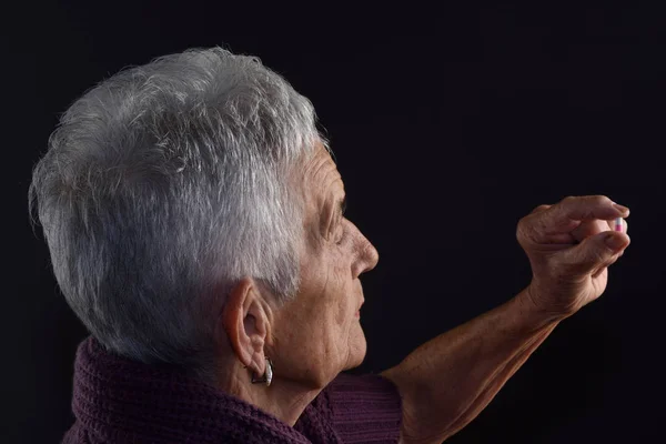 Femme âgée à la recherche d'une pilule avec fond gris — Photo