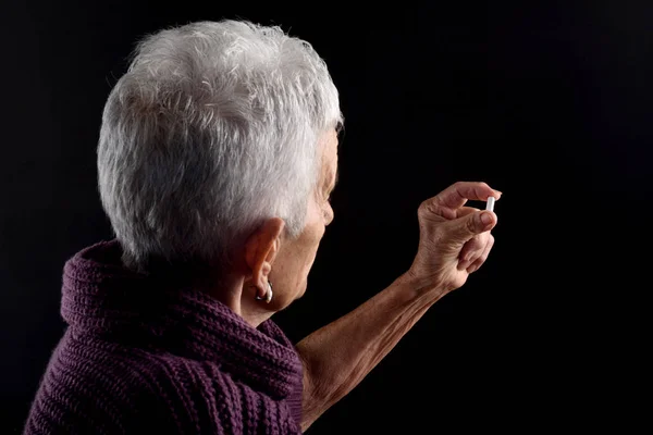 Mujer mayor buscando una píldora de color blanco — Foto de Stock