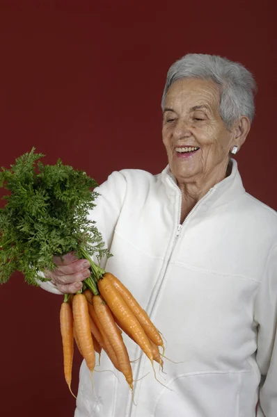 Senior woman with carrots — Stock Photo, Image