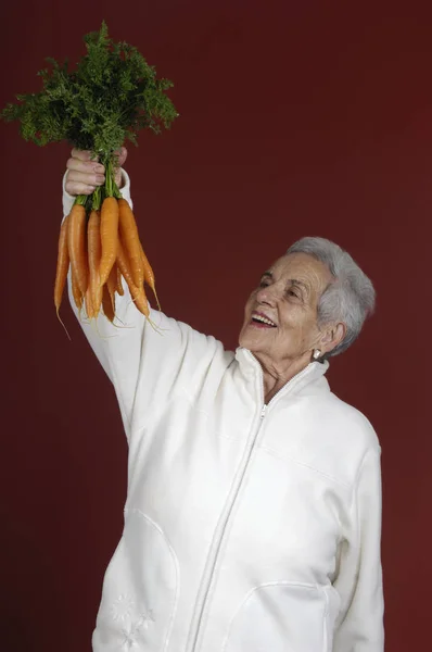 Senior woman with carrots — Stock Photo, Image