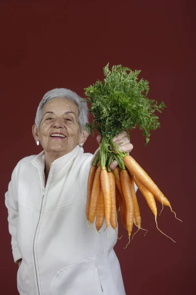 Senior woman with carrots — Stock Photo, Image