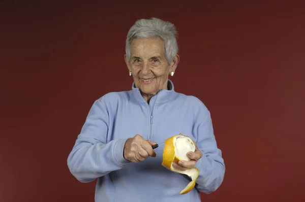 Senior Kvinna peel orenge — Stockfoto