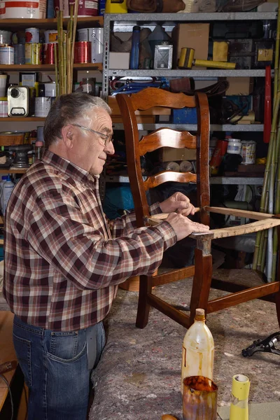 Älterer Mann restauriert einen Stuhl — Stockfoto