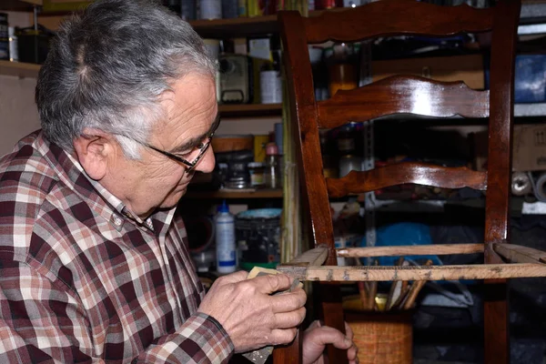 Uomo più anziano ripristino di una sedia — Foto Stock