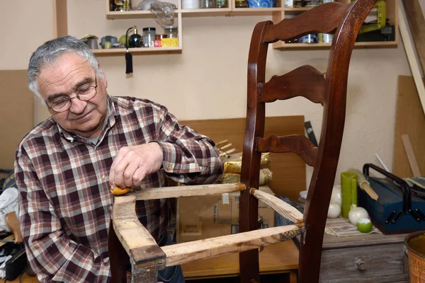 Uomo più anziano ripristino di una sedia — Foto Stock
