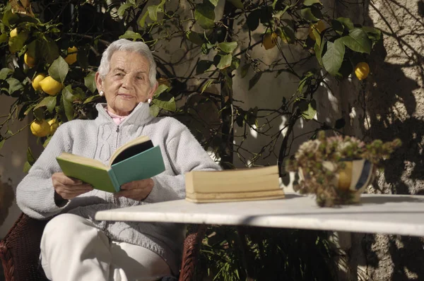 Old woman reading a book outdoors — Stock Photo, Image