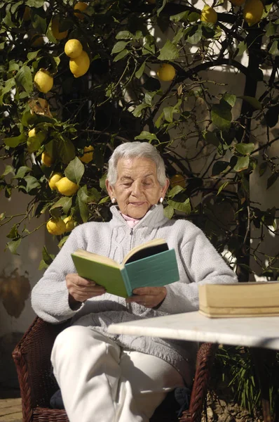 Mulher velha lendo um livro ao ar livre — Fotografia de Stock