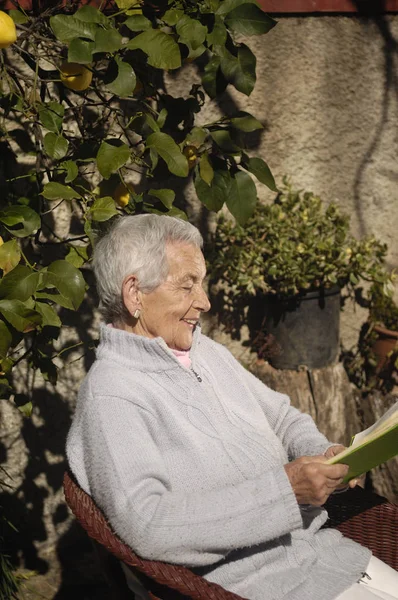 Oude vrouw lezen van een boek buiten — Stockfoto