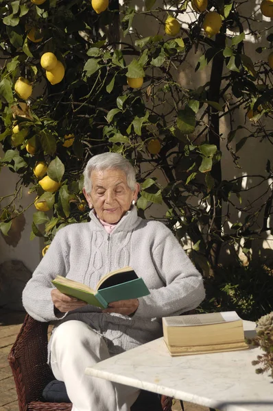 Mulher velha lendo um livro ao ar livre — Fotografia de Stock