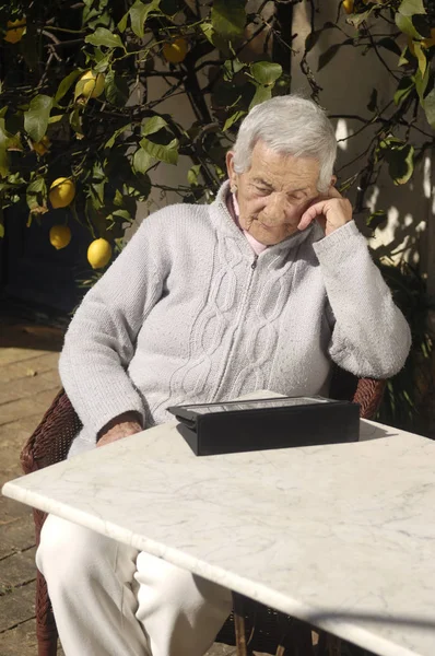 Mulher velha com uma mesa lá fora — Fotografia de Stock
