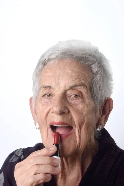 Mulher velha pintando seus lábios no fundo branco — Fotografia de Stock