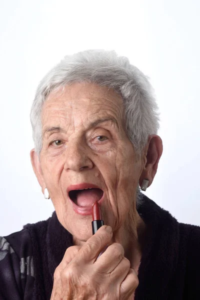 Oude vrouw schilderij van haar lippen op witte achtergrond — Stockfoto
