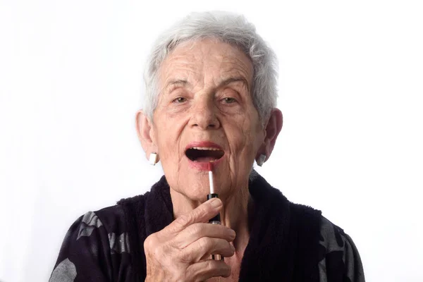 Oude vrouw schilderij van haar lippen op witte achtergrond — Stockfoto