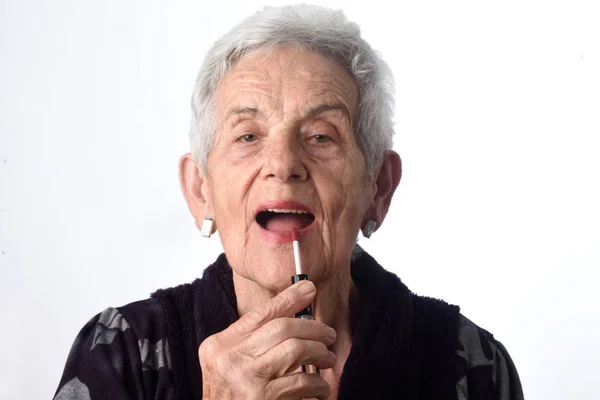 Mujer vieja pintando sus labios sobre fondo blanco — Foto de Stock