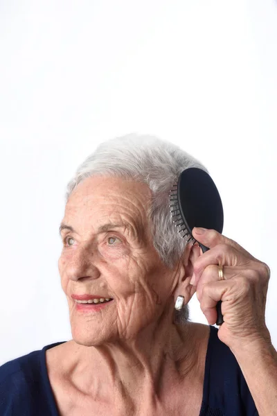 Mujer mayor peinándose el pelo sobre fondo blanco —  Fotos de Stock