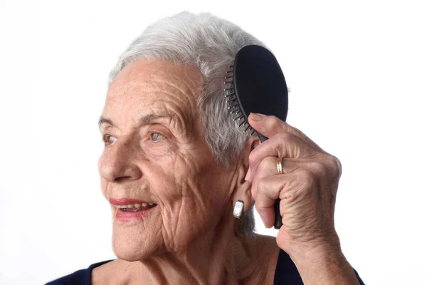 Mujer mayor peinándose el pelo sobre fondo blanco —  Fotos de Stock