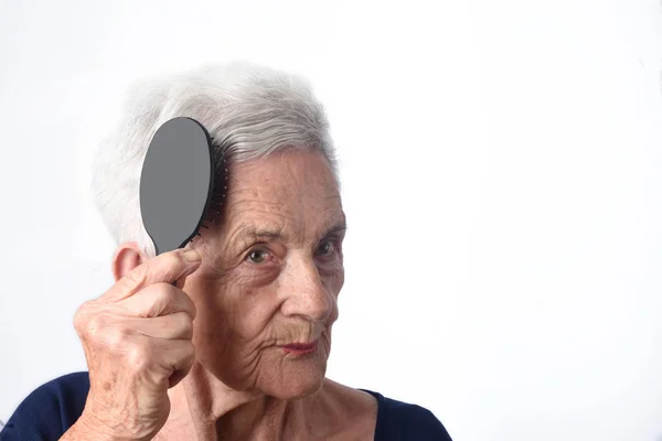 Senior vrouw kammen van haar haren op witte achtergrond — Stockfoto