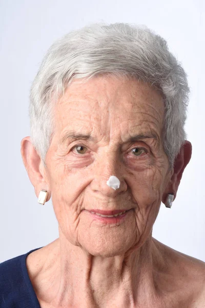 Senior vrouw toepassing huid crème of crème op haar gezicht — Stockfoto