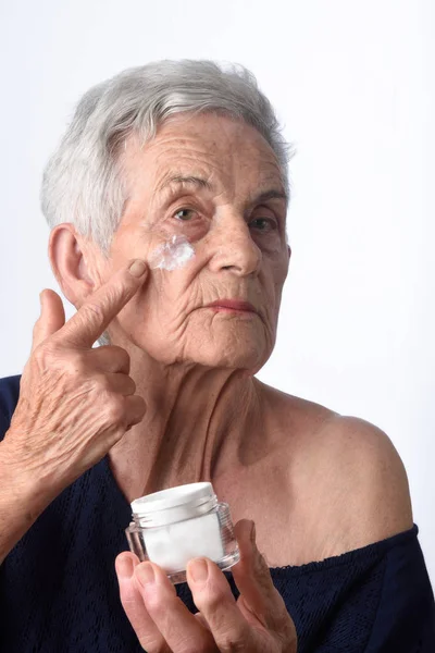 Старша жінка наносить крем для шкіри або зволожувач для обличчя — стокове фото