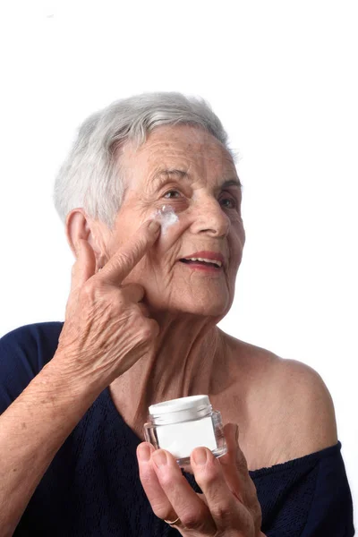 Старша жінка наносить крем для шкіри або зволожувач для обличчя — стокове фото