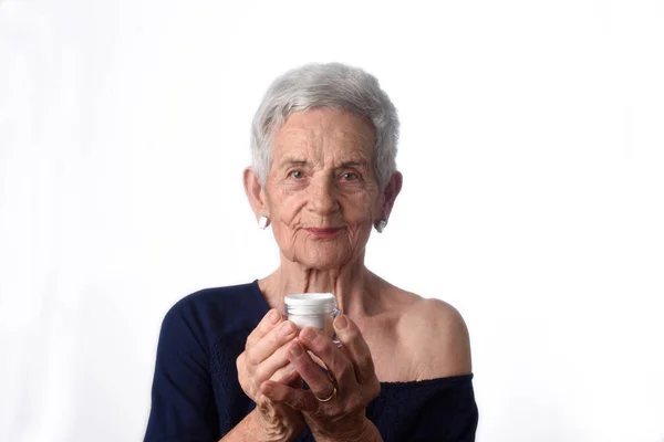 Senior vrouw toepassing huid crème of crème op haar gezicht — Stockfoto