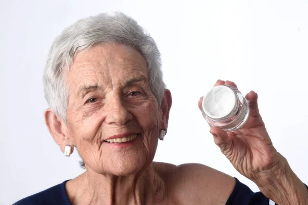 Senior vrouw toepassing huid crème of crème op haar gezicht — Stockfoto