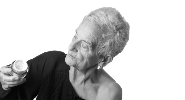 Senior Kvinna tillämpa hudkräm eller fuktkräm till hennes ansikte — Stockfoto