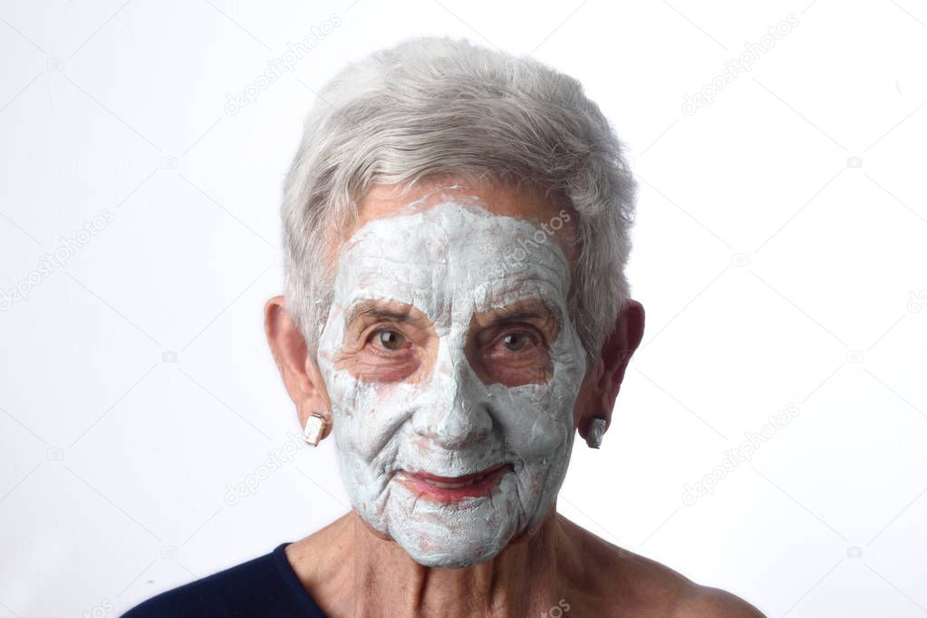 Senior woman with facian mask on white
