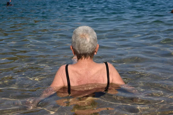 Oudere vrouw badend in de zee, — Stockfoto