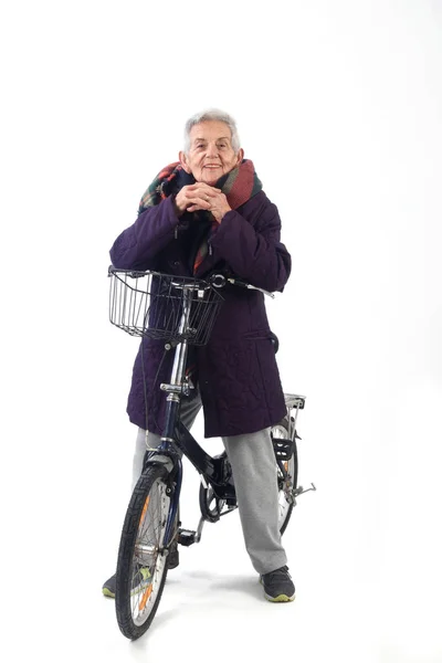 Senior Kvinna poserar med en cykel på vit bakgrund — Stockfoto