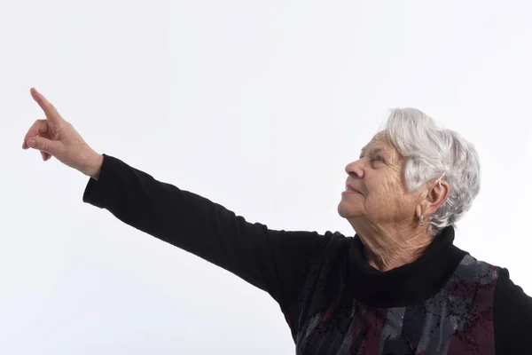 Bejaarde vrouw wijst op wit — Stockfoto