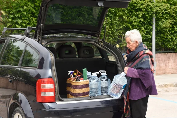 Mulher velha baixando a compra de carro — Fotografia de Stock